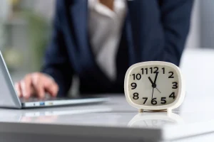 un homme devant un ordinateur avec une montre posée sur la table