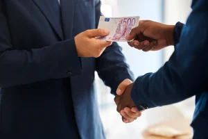 Deux hommes qui se serrent la main et l'autre tend de l'argent