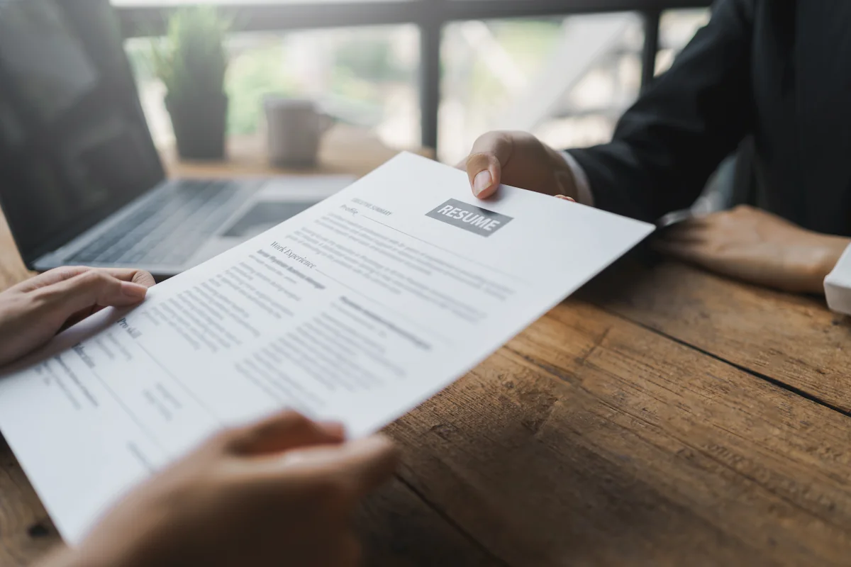 Une personne qui tend son CV développeur web