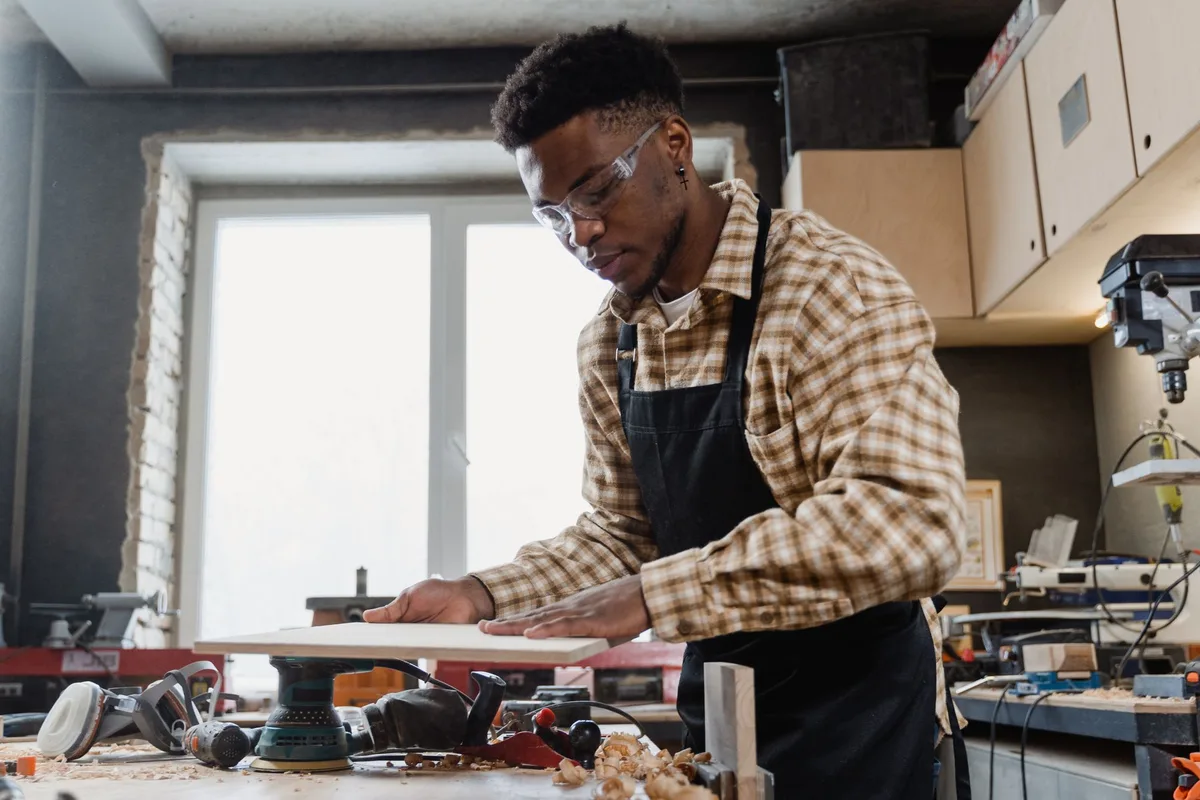 Un artisan en tablier et lunettes de protection au travail dans un atelier