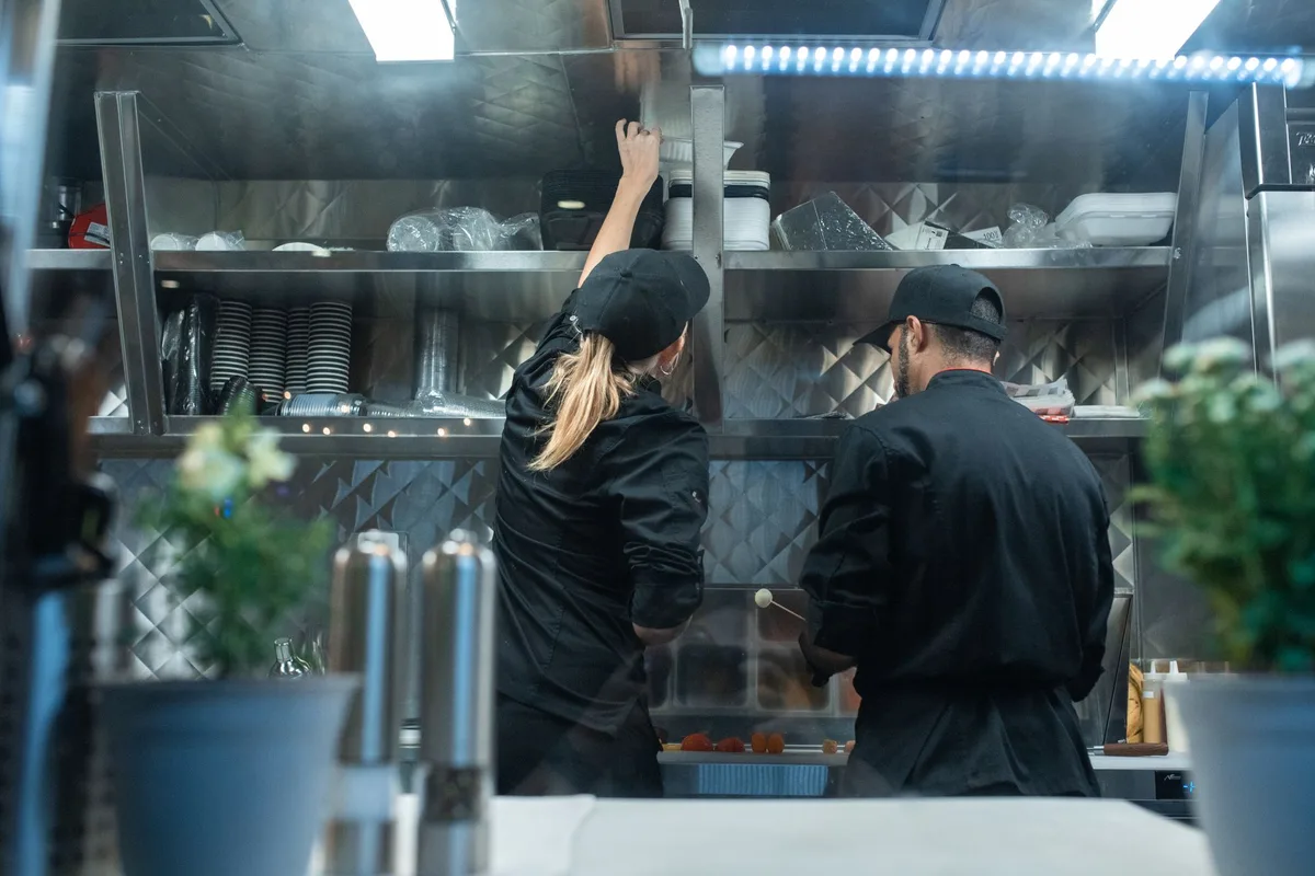 Deux cuisiniers en tenue noire au travail dans une cuisine professionnelle