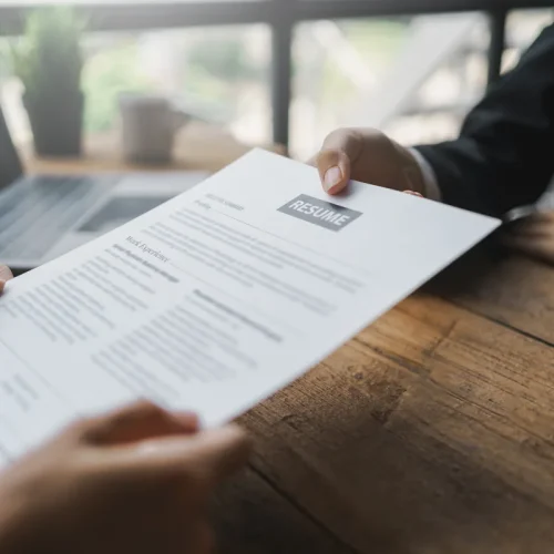 Une personne qui tend son CV développeur web